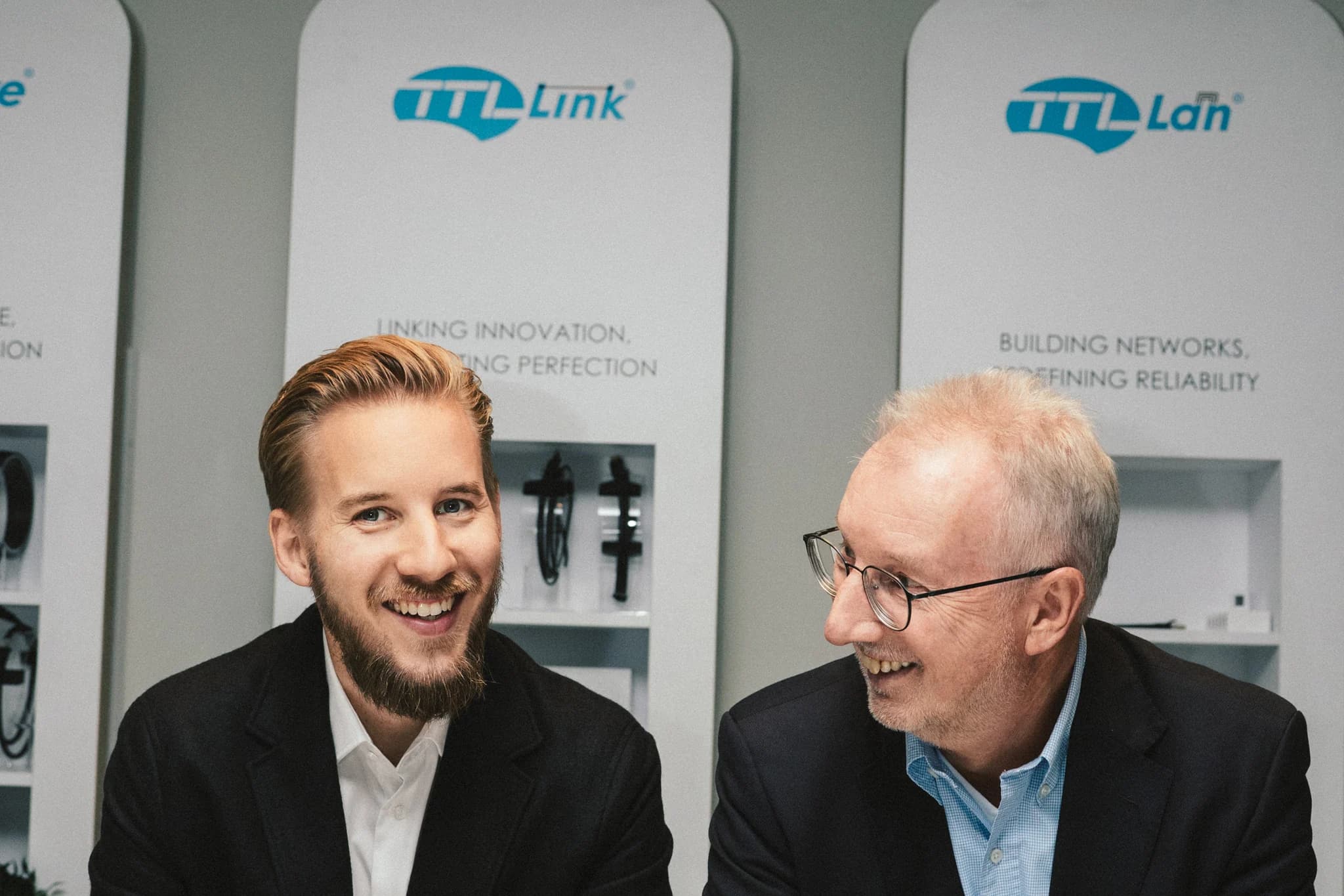 The two managing directors of TTL Network at the table in front of the TTL Link® and TTL Lan® brand displays