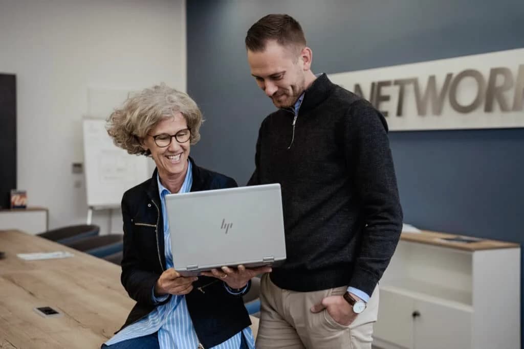 Two TTL employees discussing a task at a workstation.