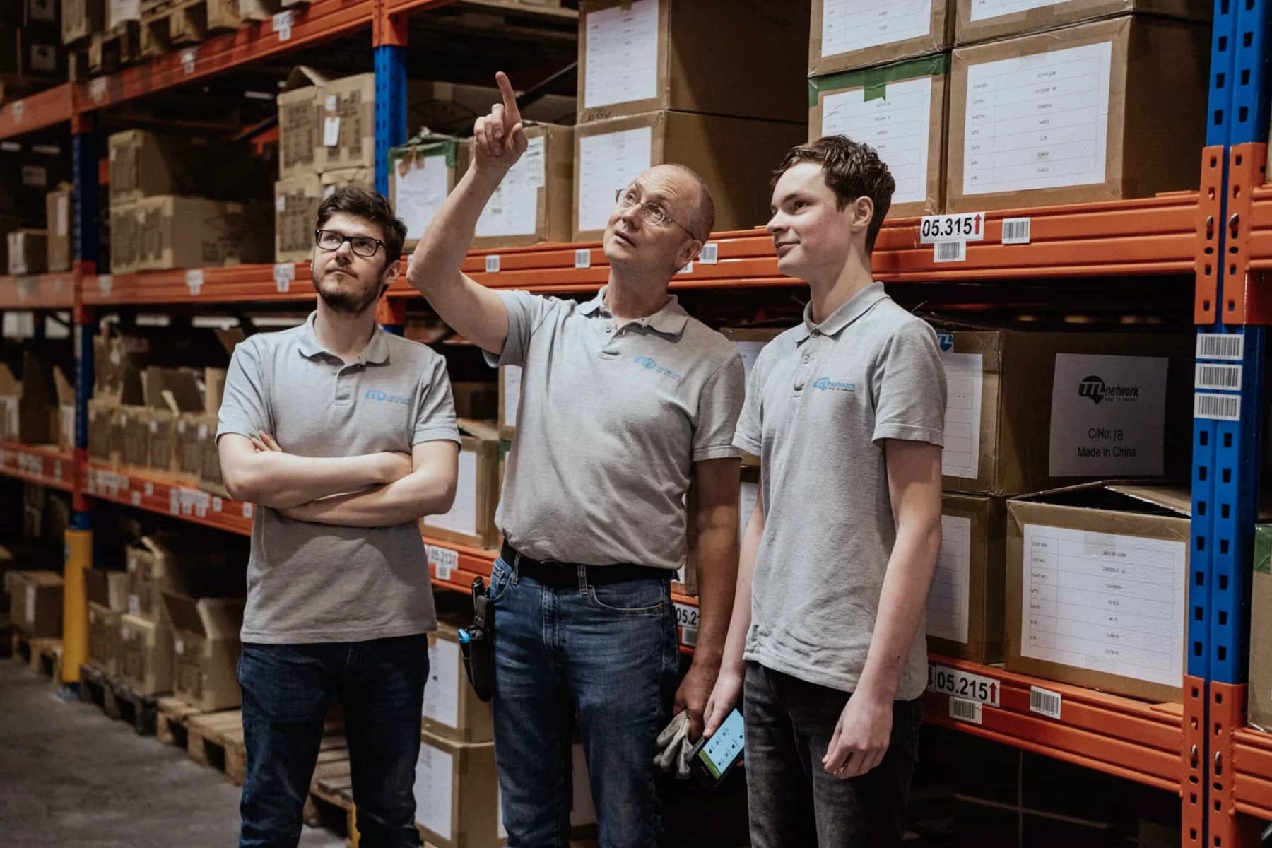 Three TTL employees coordinating between the warehouse racks