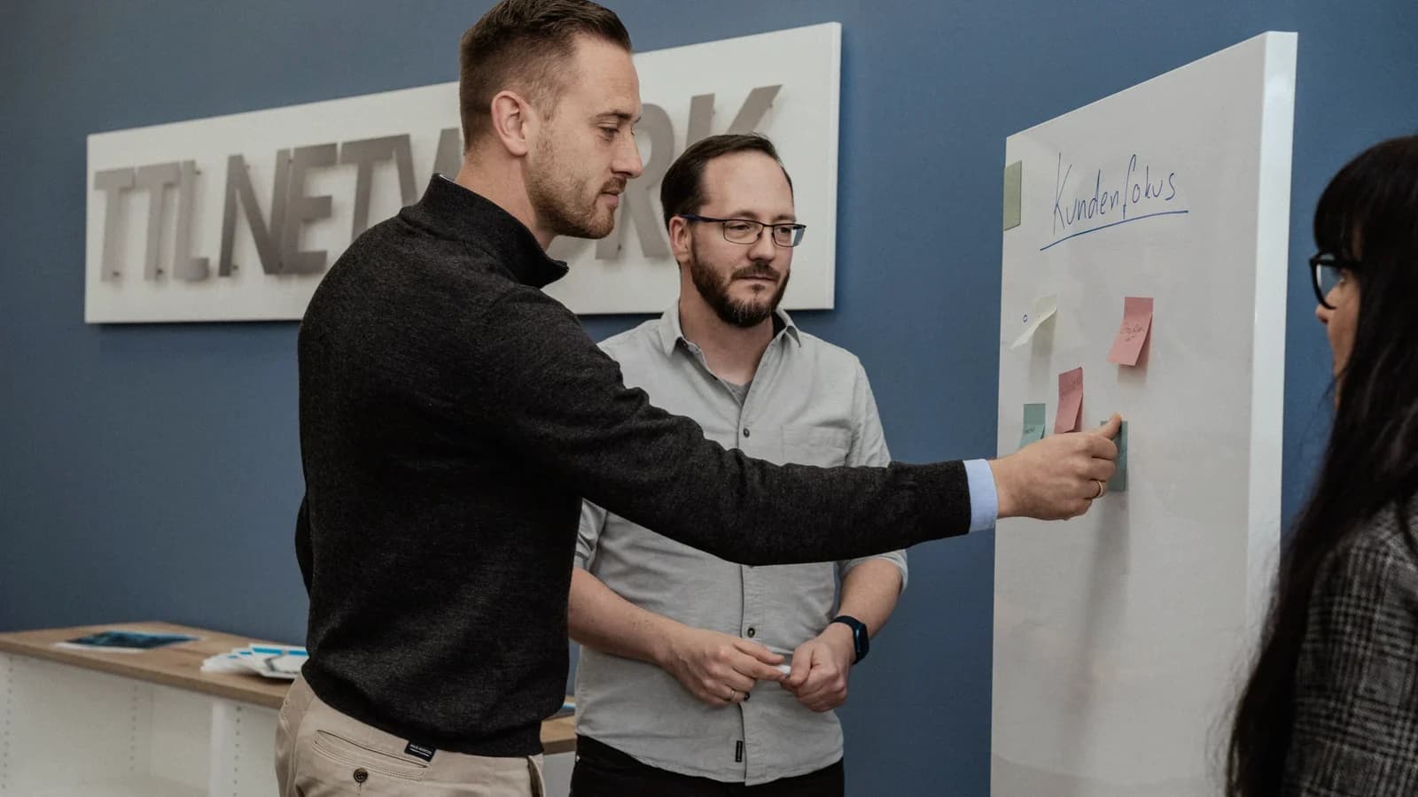 Colleagues pinning notes on the topic of customer focus to a whiteboard