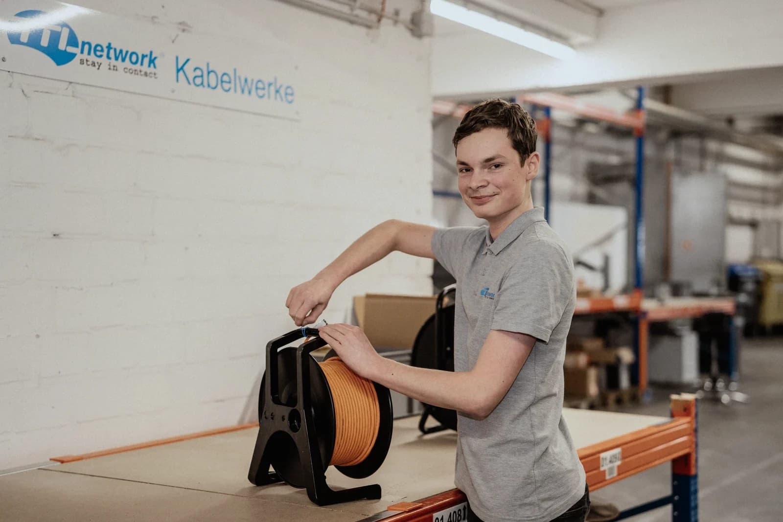 Apprentice with a cable drum at a workbench in the warehouse