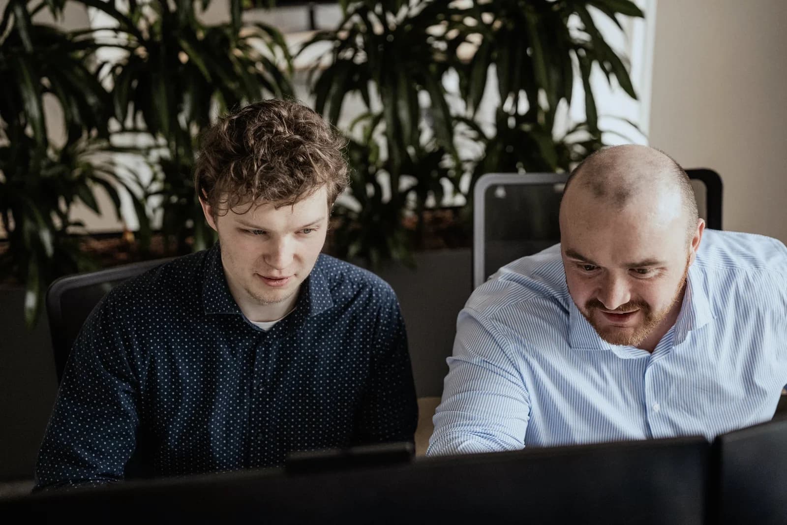 Two colleagues together at a screen in the office